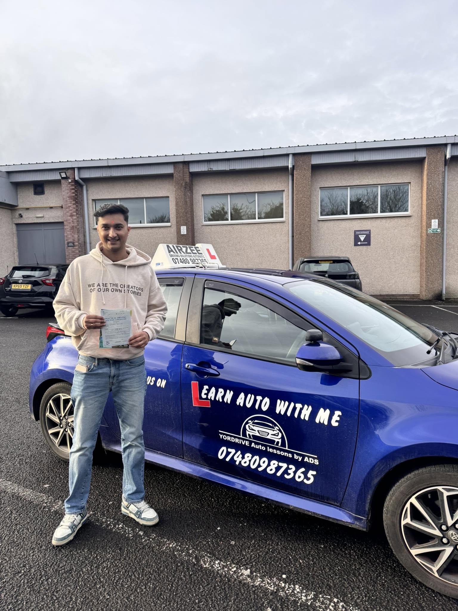 YorDrive learner celebrating with practical driving test pass certificate, blue training car