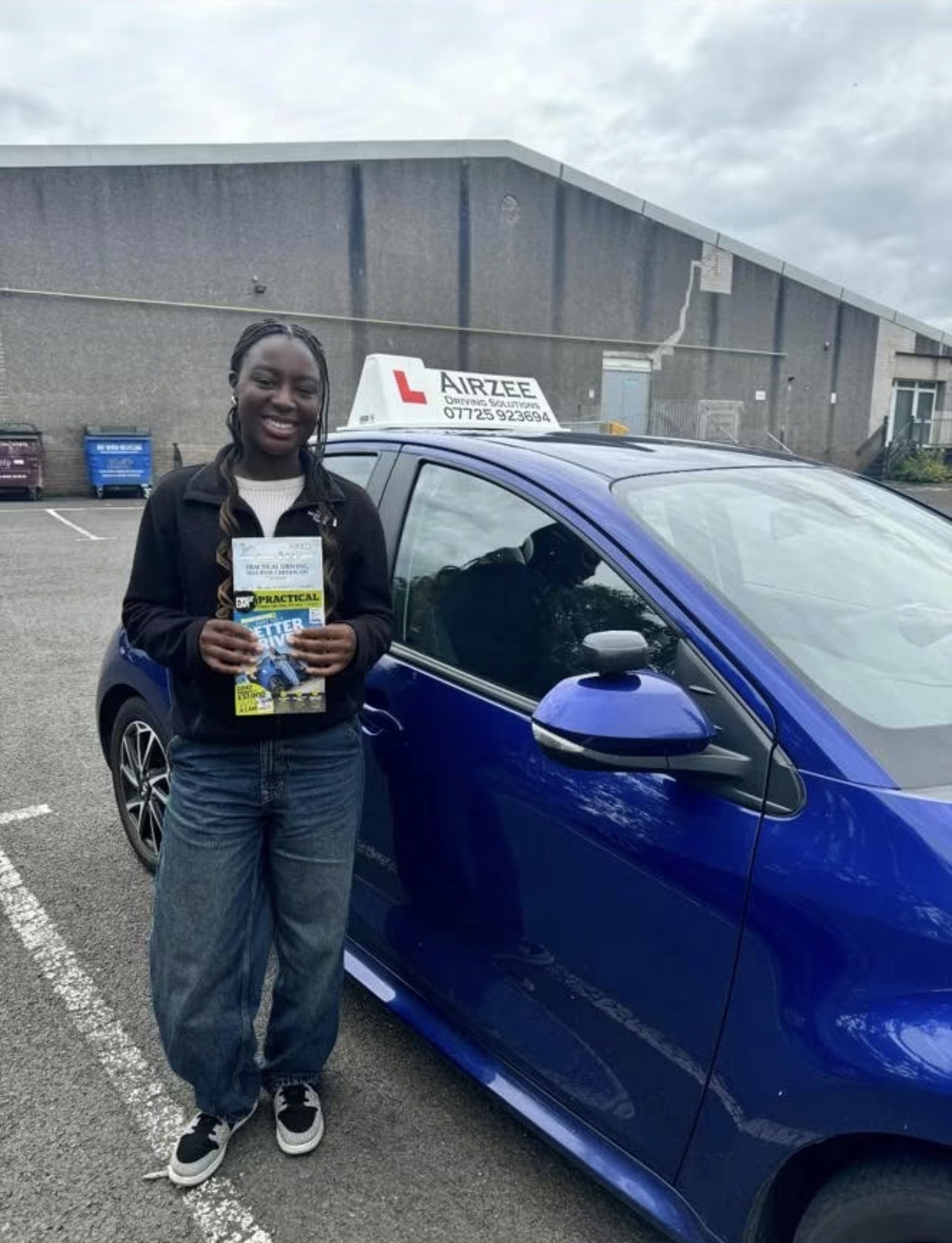 YorDrive learner celebrating with practical driving test pass certificate, blue Airzee training car