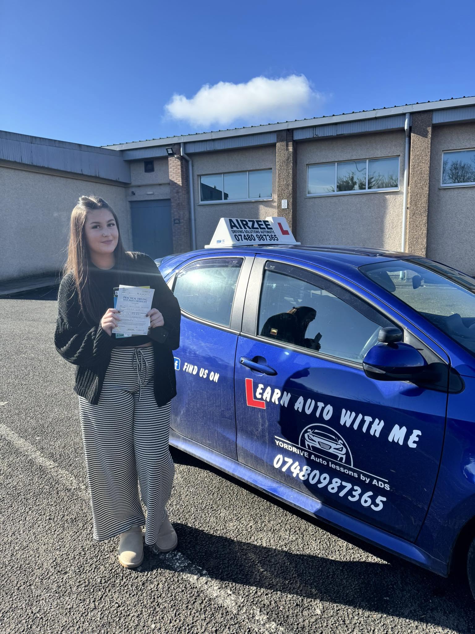 YorDrive learner celebrating with practical driving test pass certificate, blue Airzee training car